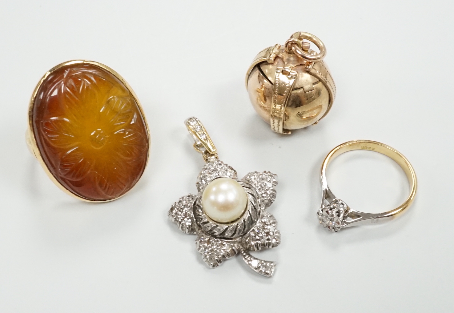 A 9ct masonic ball pendant, 18mm, a 750 white metal cultured pearl and diamond chip set flower head pendant, 38mm, a yellow metal ring and an 18ct and illusion set diamond ring.